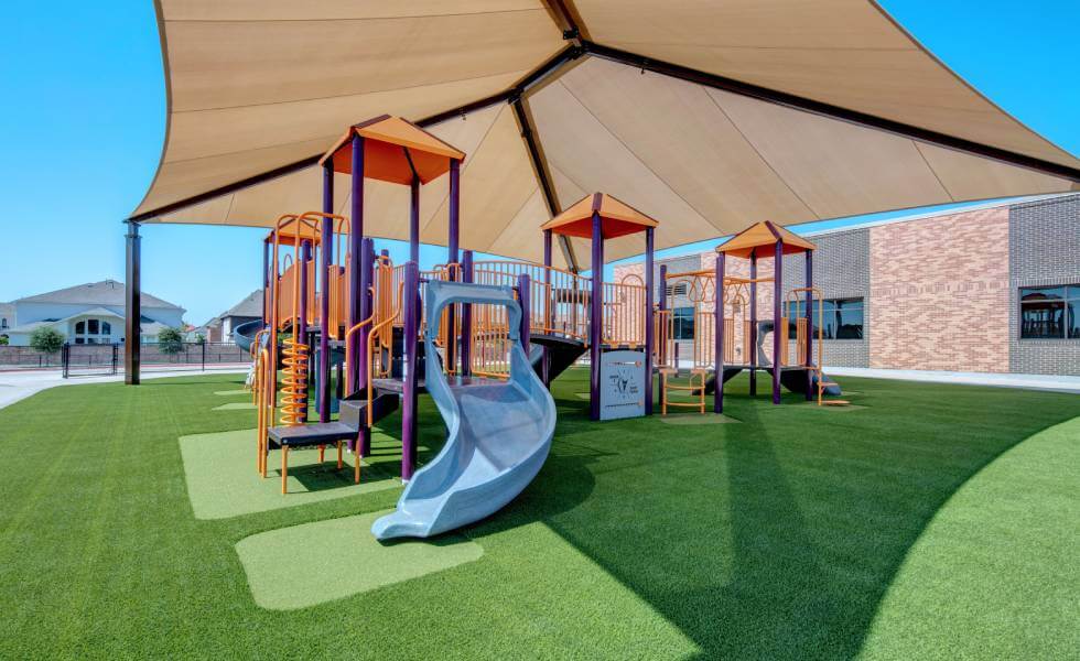playground with artificial turf and a multi colored jungle gym